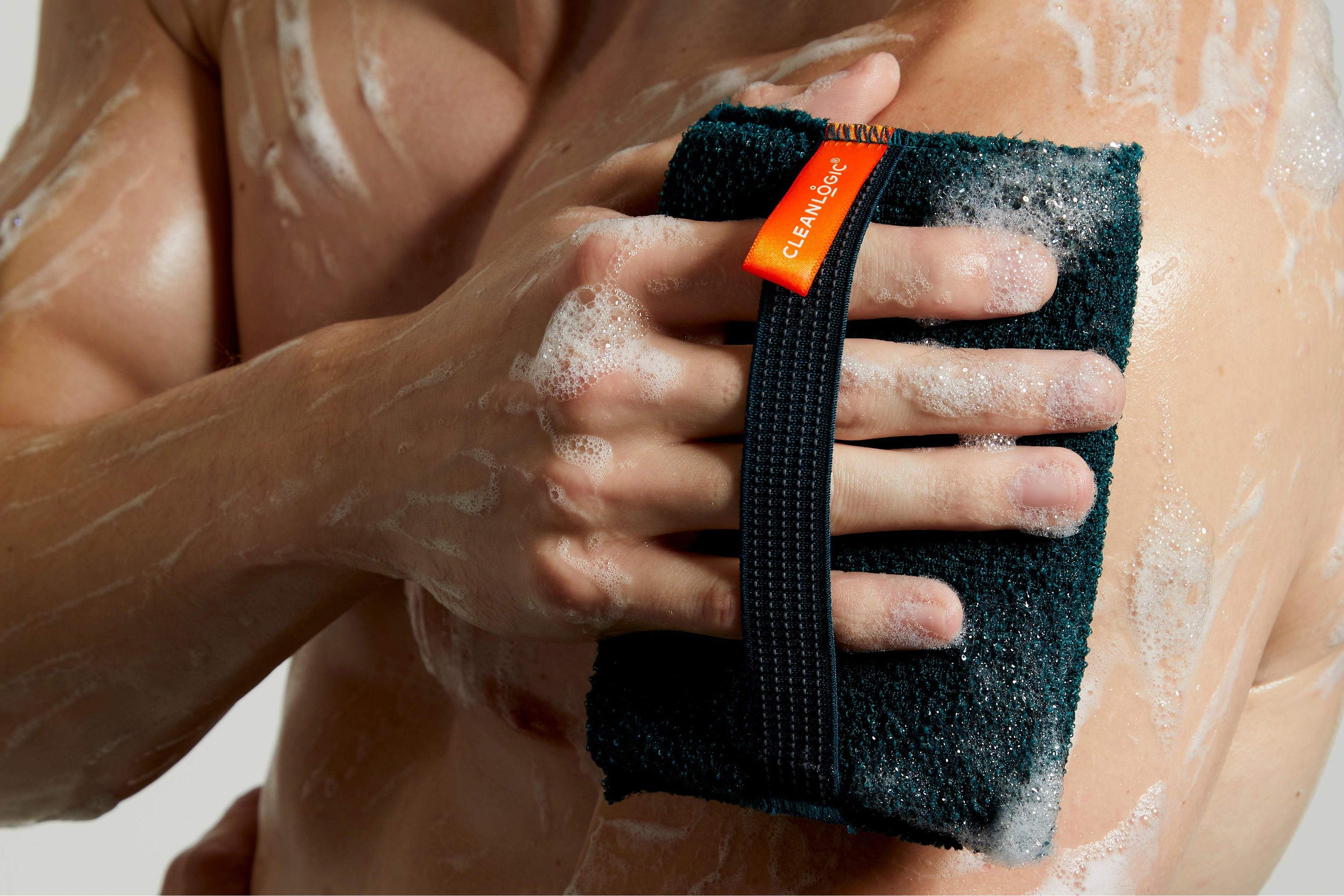 Man using a black scrubber with orange label on a white background