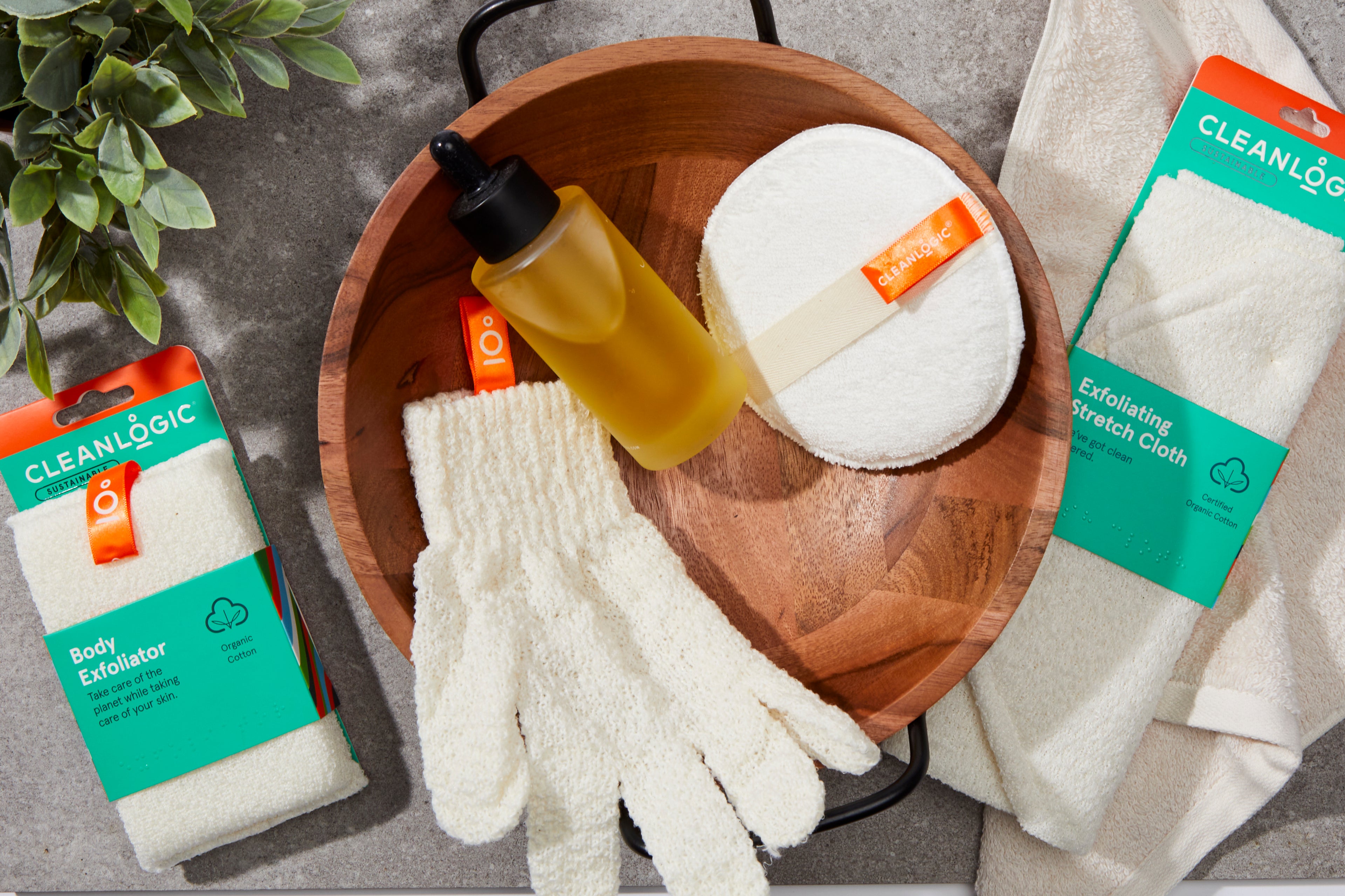 Skincare products including a bottle, gloves, and cloths on a wooden tray with 'Cleanlogic' packaging.