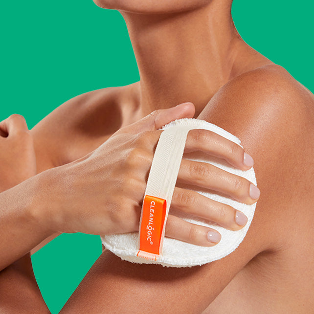 Person using a white exfoliating pad with an orange label on a green background